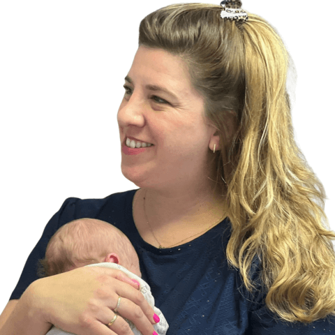 אישה בלונדינית מחייכת אוחזת תינוק ישן על רקע לבן, אימהות.